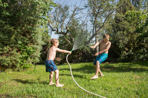 Kleine Kinder in Badekleidung, die herumrennen und sich gegenseitig mit Wasser aus dem Gartenschlauch bespritzen - ADSF10158