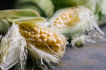 Top view of steps of fresh ripe corn peeling on black table - ADSF10168
