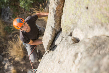 Von oben: Mann klettert mit Kletterausrüstung auf einen Felsen in der Natur - ADSF10176