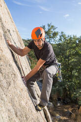 Mann klettert mit Kletterausrüstung auf einen Felsen in der Natur - ADSF10181