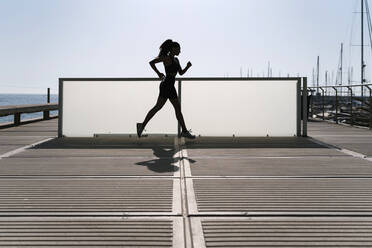 Frau beim Sport am Hafen gegen den klaren Himmel an einem sonnigen Tag - EGAF00644