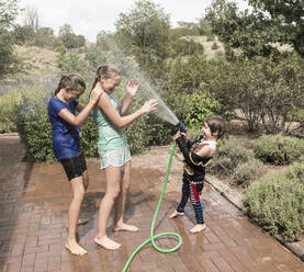 Children spraying each other with water hose - MINF15014