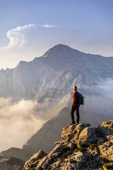 Wanderer steht und bewundert die Aussicht auf einen Berg in den Bergamasker Alpen, Italien - MCVF00559
