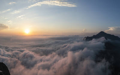 Idyllische Aufnahme eines von Wolken bedeckten Berges bei Sonnenaufgang in den Bergamasker Alpen, Italien - MCVF00564