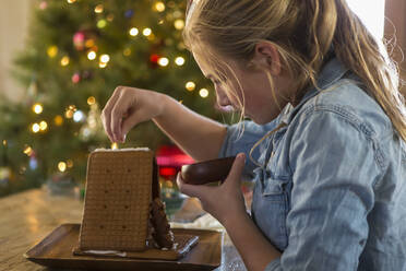 11 year old girl building a ginger bread house at home - MINF15045