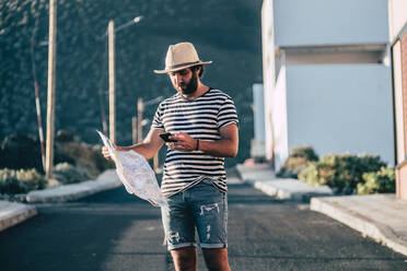 Male traveler standing with map and smartphone - ADSF10234