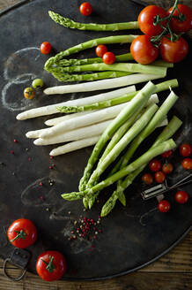 Pfefferkörner, Tomaten und Spargelstangen auf rustikalem Backblech - ASF06657