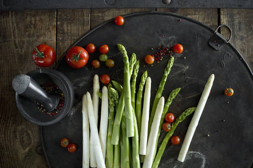 Mörser und Stößel, Pfefferkörner, Tomaten und Spargelstangen auf rustikalem Backblech - ASF06659