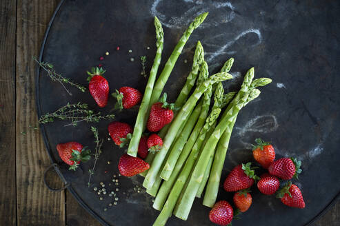 Thymian, Pfefferkörner, Spargelstangen und frische Erdbeeren auf rustikalem Backblech - ASF06663