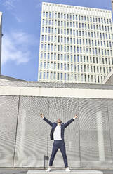 Entrepreneur with arms raised standing on concrete block in city - VEGF02642