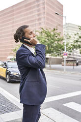 Businessman talking on smart phone in city - VEGF02646
