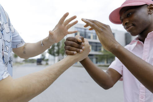 Lächelnder Mann, der sich mit einem männlichen Freund in der Stadt trifft - KMKF01450