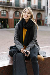 Young woman with violin case using smartphone in city - RDGF00016