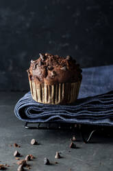 Leckerer Muffin mit Schokolade und Banane auf blauem Handtuch an grauer Wand - ADSF10331