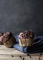Leckerer Muffin mit Schokolade und Banane auf blauem Handtuch an grauer Wand - ADSF10333