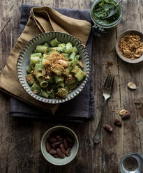 From above bowl of palatable pasta paccheri with fresh kale pesto and ground peanuts on timber tabletop - ADSF10336