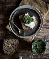 Von oben Teller mit leckerem Roggentoast mit Käse und frischem Pesto auf Holztischplatte - ADSF10361