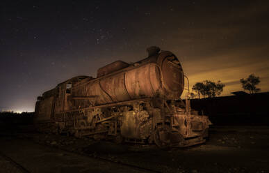 Alter verlassener Retro-Zug auf Schienen zwischen Feld und Himmel mit Sternen am Abend in Rio Tinto, Spanien - ADSF10372