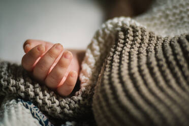 Closeup Hand von anonymen schlafenden Baby unter weichen gestrickten Decke im Kinderzimmer liegen - ADSF10375