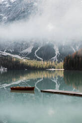 Idyllic landscape lake with wooden boats in snowy Dolomites mountains in Italy - ADSF10423