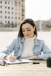 Junge Frau studiert an einem Tisch auf dem Universitätscampus - RDGF00039