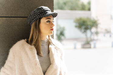 Beautiful woman in jacket looking away against wall - RDGF00052