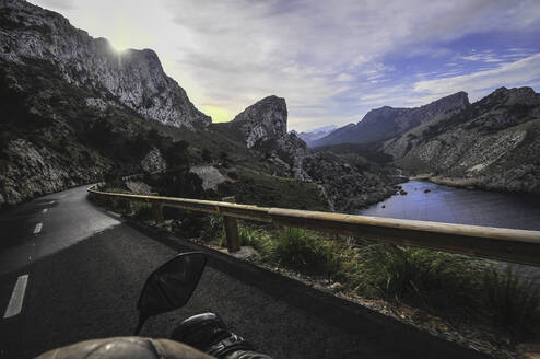Von oben der Ernte Fahrer fahren Motorrad auf der Straße von Bergen in der Nähe von See gegen bewölkten Himmel umgeben - ADSF10547