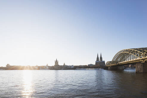 Germany, North Rhine-Westphalia, Cologne, Sun setting over Rhine with Hohenzollern Bridge and Cologne Cathedral in background - GWF06708