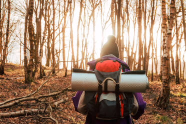 Rückenansicht eines anonymen Wanderers in warmer Kleidung, der tagsüber durch einen Herbstwald läuft - ADSF10576