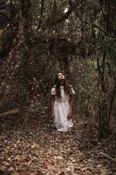 Mysterious calm female in white dress standing in calm autumnal park - ADSF10676