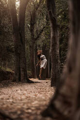 Mysterious calm female in white dress jumping levitating in calm autumnal park - ADSF10681