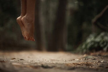 Crop female bare feet jumping above ground in autumnal forest on blurred background - ADSF10682