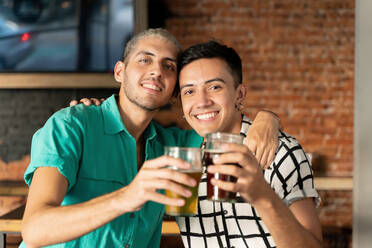 Happy gay couple with arm around holding beer glass at bar - SPCF00842