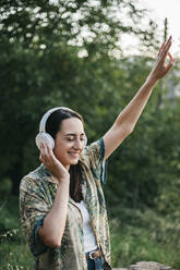 Glückliche Frau tanzt bei Musik in einem öffentlichen Park - XLGF00457