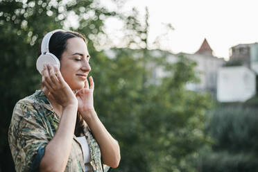 Woman with eyes closed listening music through headphones - XLGF00458