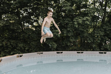 Boy jumping into swimming pool - SMSF00157