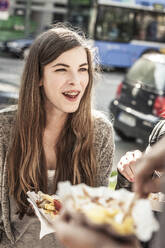 Portrait of a teenage girl hanging out with friends in the city having a snack - DHEF00236