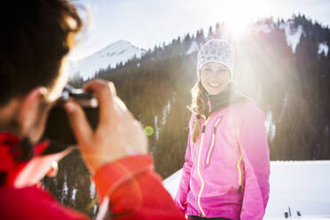 Man taking picture of woman in snow, Achenkirch, Austria - DHEF00263