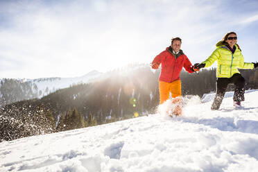 Unbekümmertes Paar beim Laufen durch den Schnee, Achenkirch, Österreich - DHEF00281