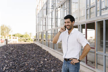 Smiling businessman talking on phone outside building - MPPF01023