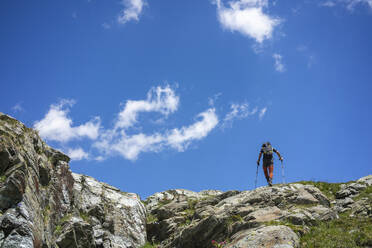 Mann beim Wandern auf dem Gipfel eines Berges in den westlichen Rätischen Alpen, Sondrio, Italien - MCVF00567