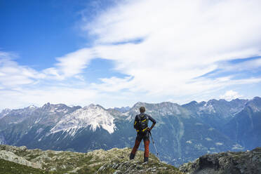Wanderer steht auf dem Gipfel und schaut auf die Berge, Westliche Rätische Alpen, Sondrio, Italien - MCVF00570