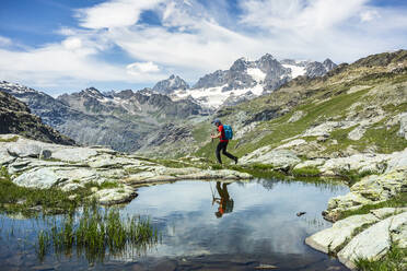 Man exploring while walking by lake at Western Rhaetian Alps, Sondrio, Italy - MCVF00572