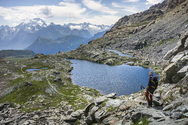 Mann beim Wandern am See in den westlichen Rätischen Alpen, Sondrio, Italien - MCVF00574