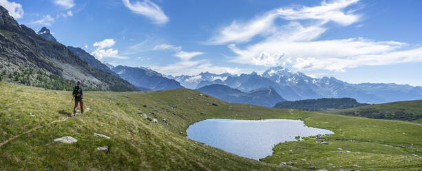 Wanderer in der Nähe eines Sees auf einem Berg in den westlichen Rätischen Alpen, Sondrio, Italien - MCVF00576