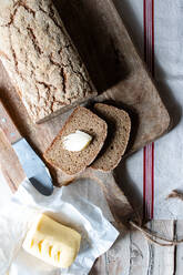 From above loaf of tasty ryecorn bread placed on cloth napkin near spoon of grain on wooden background - ADSF10781