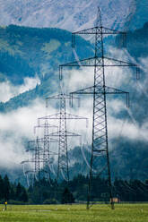 Industrial landscape of power lines in foggy stony mountains under white clouds in blue in Austria - ADSF10788