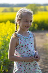 Cute little girl standing in farm of rapeseed field - JFEF00955