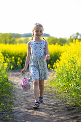 Lächelndes Mädchen, das in einem Rapsfeld spazieren geht - JFEF00958