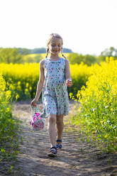 Smiling girl walking in rapeseed field - JFEF00958